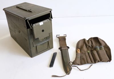 une petite boîte en métal contenant un couteau et d'autres objets, posée sur la table