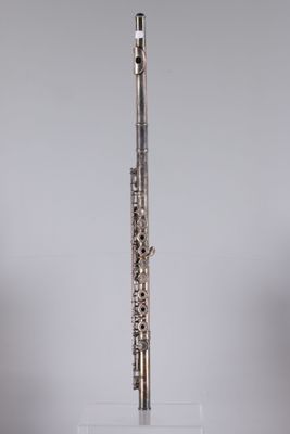 a silver flute on a clear stand against a gray background