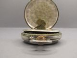 a small silver box with a shell inside of it