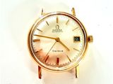 une montre en or avec un cadran blanc posée sur une surface blanche