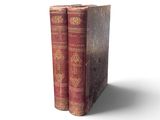two old books sitting on top of each other on a white surface