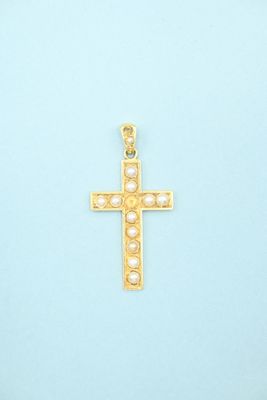 gold cross pendant with pearls on a light blue background