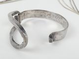 sterling cuff bracelet with a curved design on a white surface