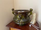 a green vase sitting on top of a table next to a phone