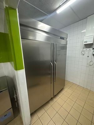 un réfrigérateur en acier inoxydable dans une cuisine avec un mur végétal