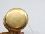 a person holding a gold pocket watch in their hand