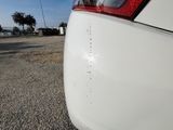 the rear end of a white car parked on the side of the road