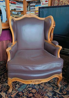 un fauteuil en cuir marron placé devant une bibliothèque