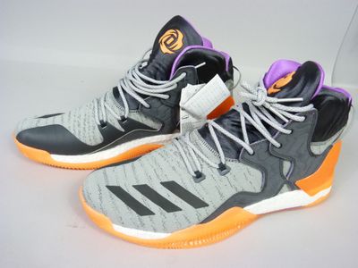 Des chaussures de basket adidas sur un fond blanc, ornées d'une bande violette et orange