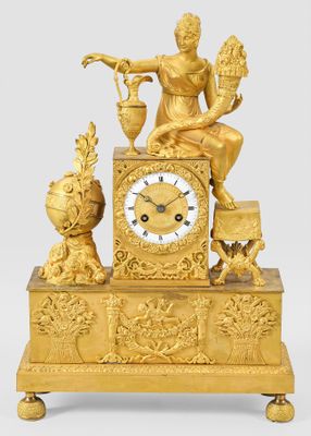 a gold clock with a statue of a man sitting on top of it