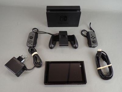 une console Nintendo Wii posée sur une table, à côté d'un chargeur et d'autres accessoires