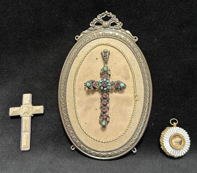 three pieces of jewelry including a cross, a locke, and a pendant