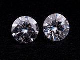 two round brilliant cut diamonds on a black surface