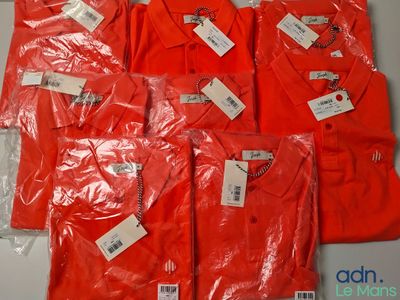 six t-shirts rouges avec leurs étiquettes, posés sur une table