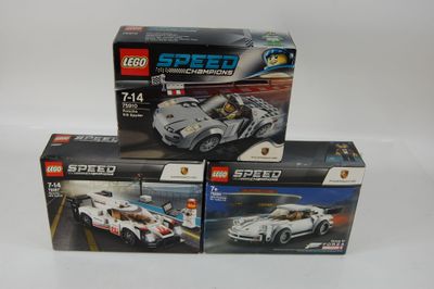 trois voitures de course Lego dans leurs boîtes, posées sur une surface blanche