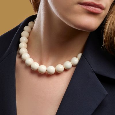 close up of a woman wearing a necklace with a pearl bead