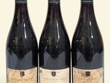 trois bouteilles de vin posées les unes à côté des autres sur une surface blanche