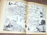 un livre ouvert posé sur une table en bois, sur laquelle figurent des dessins