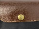 a close up of a brown leather purse with a gold button