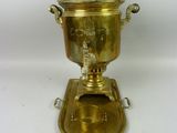 an antique brass coffee urn on a stand with a lid