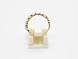 a gold and diamond ring on a white marble stand