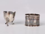 silver plated cup next to a silver plated spoon on a white surface