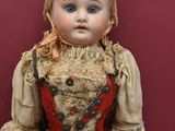 an old fashioned doll with a red dress and a brown hat