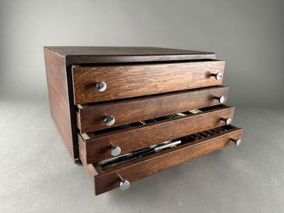 an image of a wooden drawer with four drawers and a pen in it