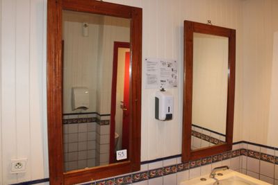 une salle de bains équipée d'un lavabo, d'un miroir et d'un distributeur de papier toilette