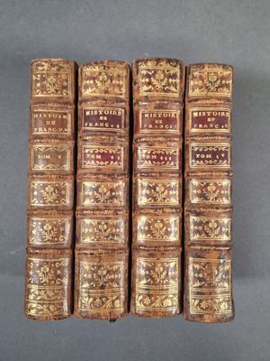 six vieux livres alignés en rangées sur une surface grise