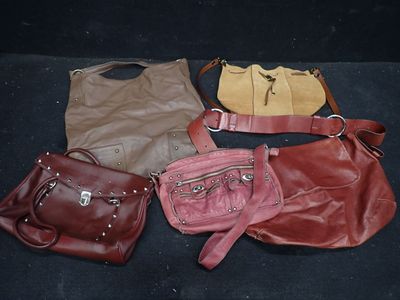quatre sacs à main sont alignés sur une surface noire