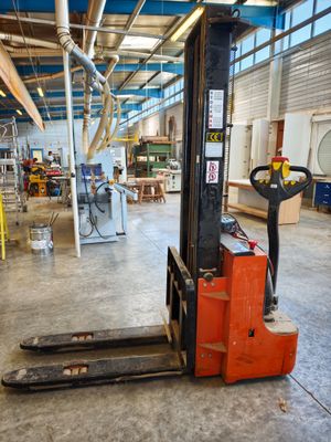 a forklift in a large warehouse with lots of work on it