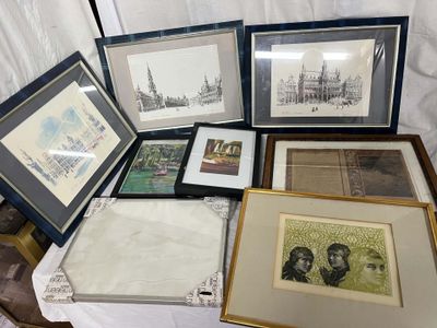 a lot of framed pictures on a table with a white table cloth