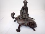 statue en bronze représentant une femme chevauchant une tortue sur le dos de laquelle se trouve un oiseau