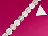 an image of a close up of a bracelet on a pink surface