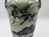 a green vase with a bird design on it