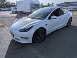 the white tesla model 3 is parked in a parking lot