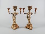 une paire de chandeliers en bois sculpté, ornés chacun d'une figurine
