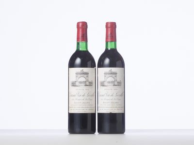 two bottles of red wine sitting on top of a table