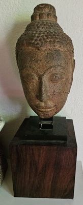 une statue représentant une tête posée sur un socle en bois