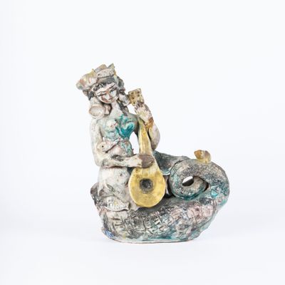 figurine of a man playing a musical instrument sitting on a rock