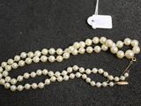 a close up of a necklace with pearls on a black surface