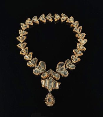 un collier en or orné d'une pierre verte et blanche au centre