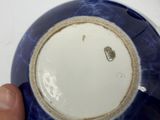 a person holding a blue and white bowl that has a small hole in it