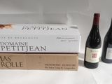 two bottles of wine sit next to a stack of books