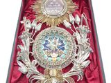 une boîte ouverte contenant une médaille et sur laquelle est posée une médaille