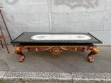 a coffee table with a black top and gold decorations on it