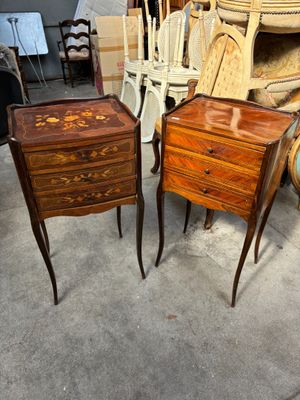 une paire de tables de chevet anciennes en bois avec des tiroirs et des chaises dans une pièce