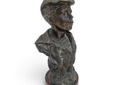 bronze bust of a boy with a hat on a wooden base