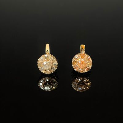 a pair of gold and diamond earrings on a black surface